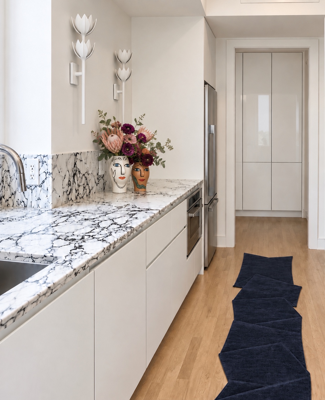 White kitchen with veined stone counters and floral face vases
