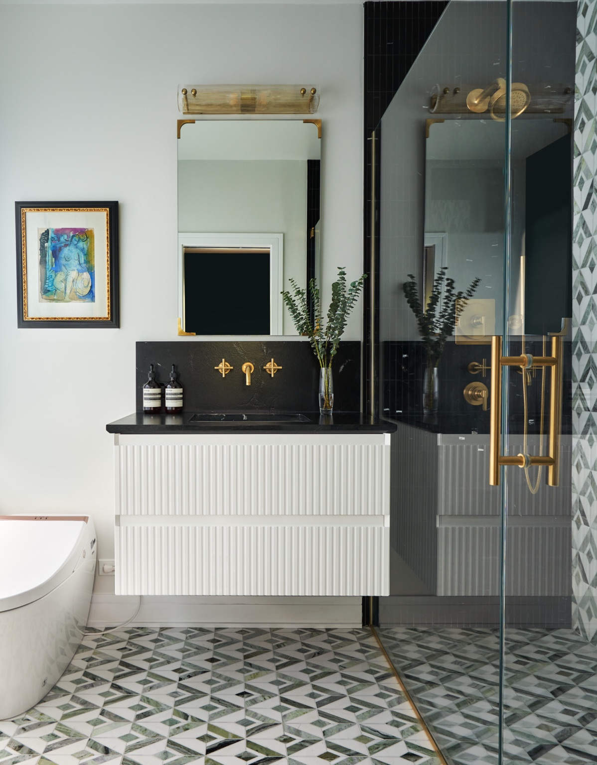 White ribbed vanity, dark countertop, gold-toned mirror and framed artwork at Dickens Avenue